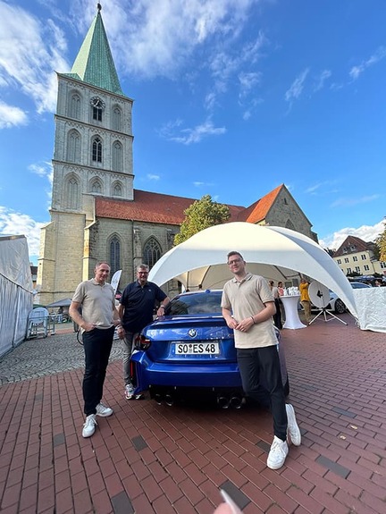 Autowelt Schmidt als Hauptsponsor bei der Hammer City Night 2025 Bernd Tolle, Sebastian Schmeißer und Norbert Dickel neben einem blauen BMW auf dem Marktplatz in Hamm bei der Hammer City Night